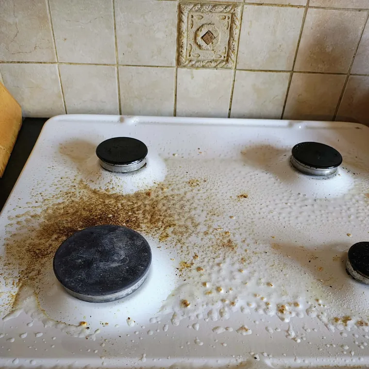 Hob before cleaning, covered in burnt-on spills and grease