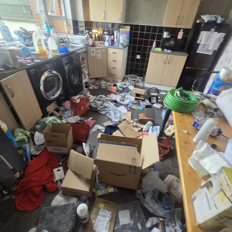 Kitchen before cleaning, floor covered in clutter and rubbish
