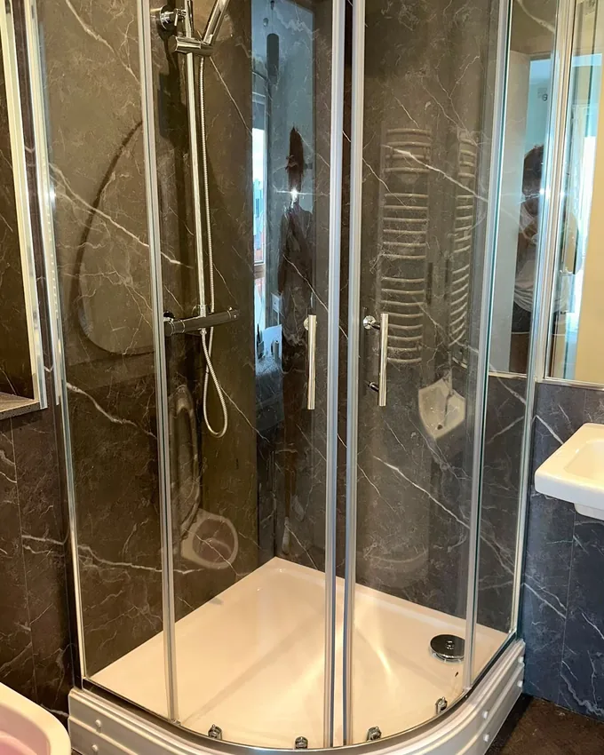 Corner shower cubicle with glass and tiles cleaned to a shine