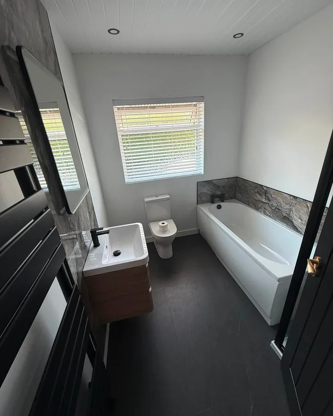 Spotless modern bathroom after a deep clean, with polished bath, basin and dark tiled floor