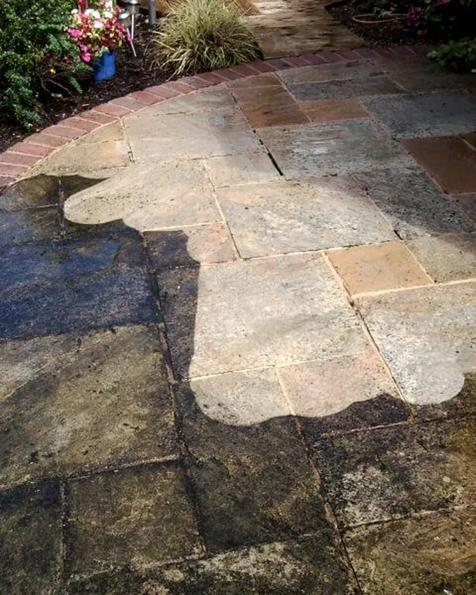 Patio halfway through pressure washing, clean stone beside untouched grime